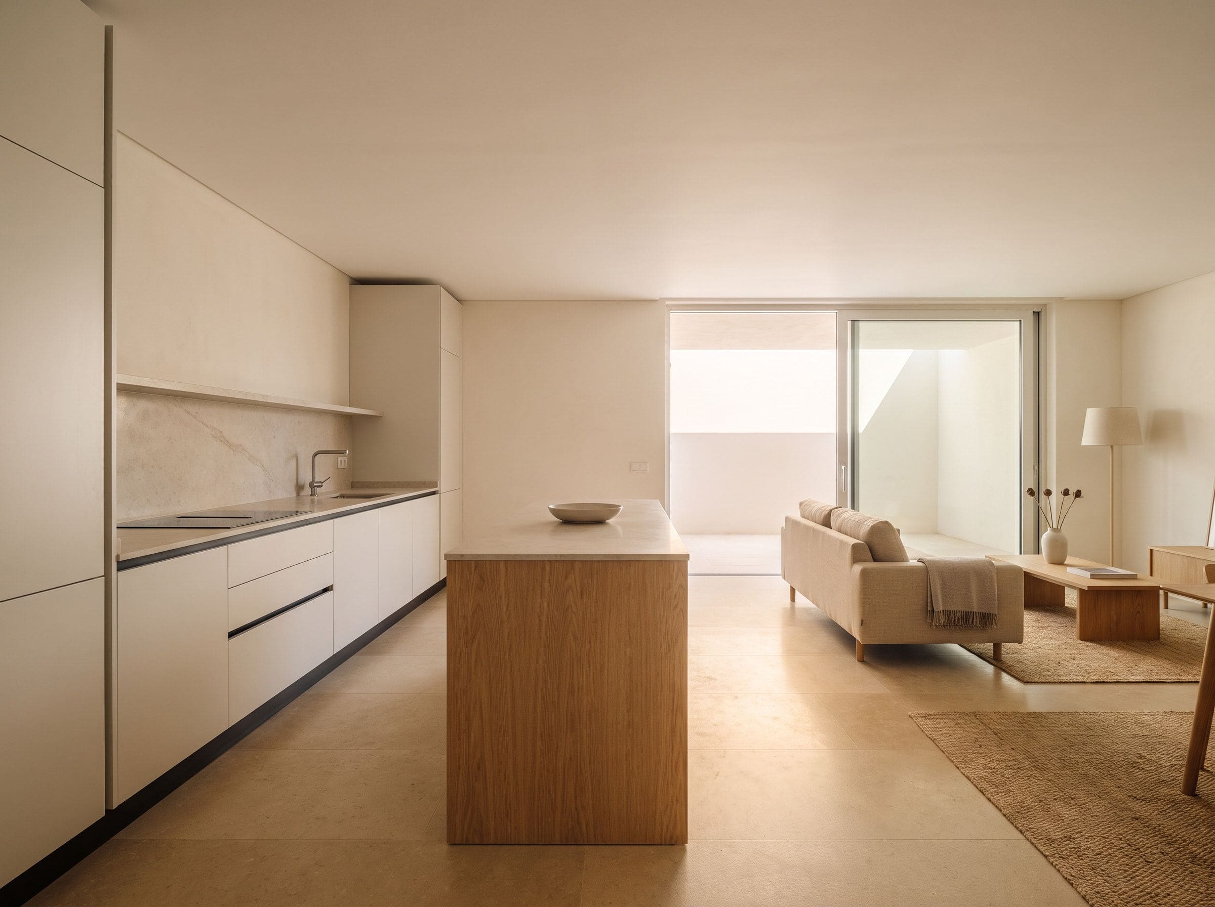 Cozinha aberta para sala de estar com ilha central e continuidade de pavimento entre as duas zonas