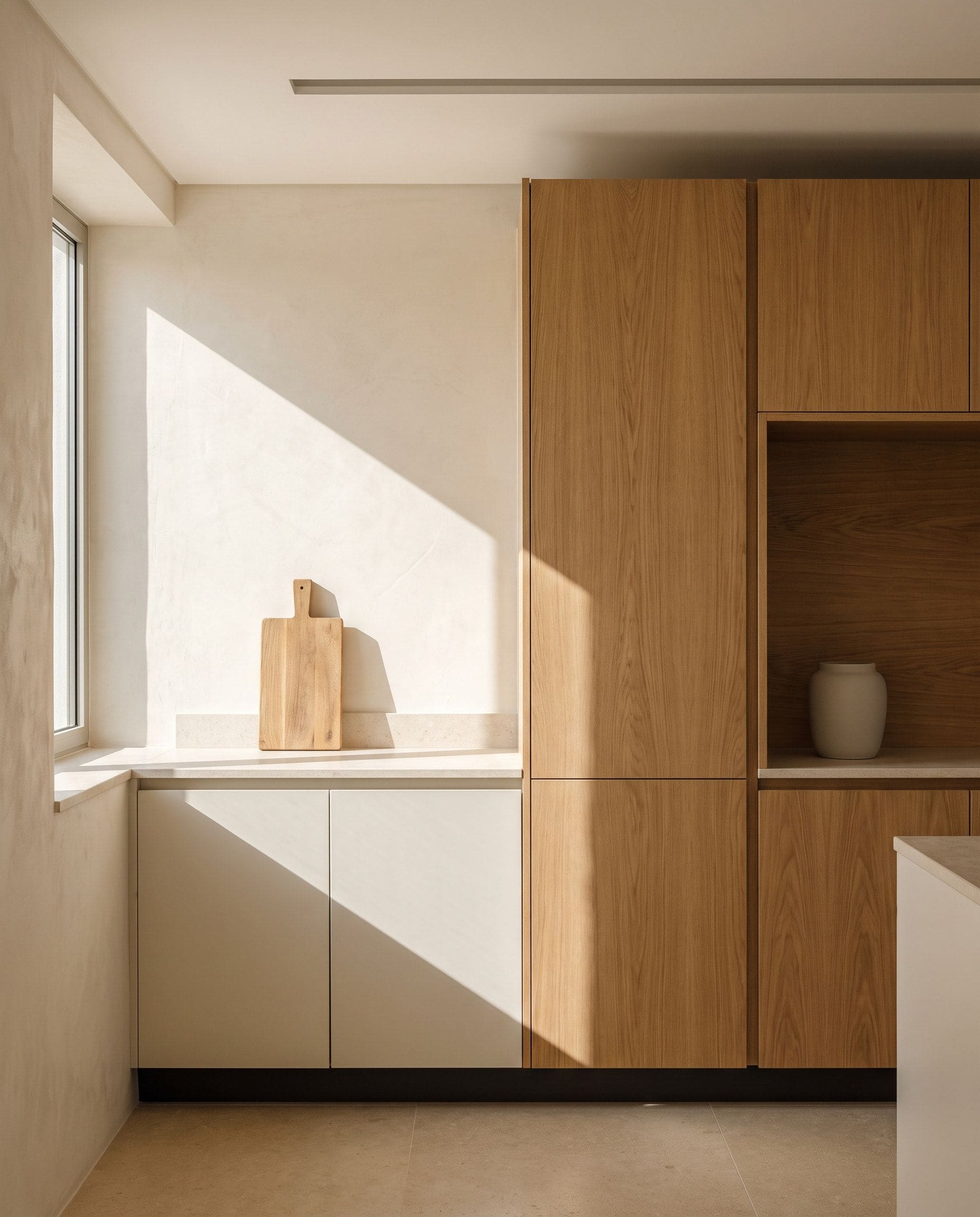 Interior de cozinha contemporânea com bancada em pedra clara, armários em tom neutro e luz natural lateral